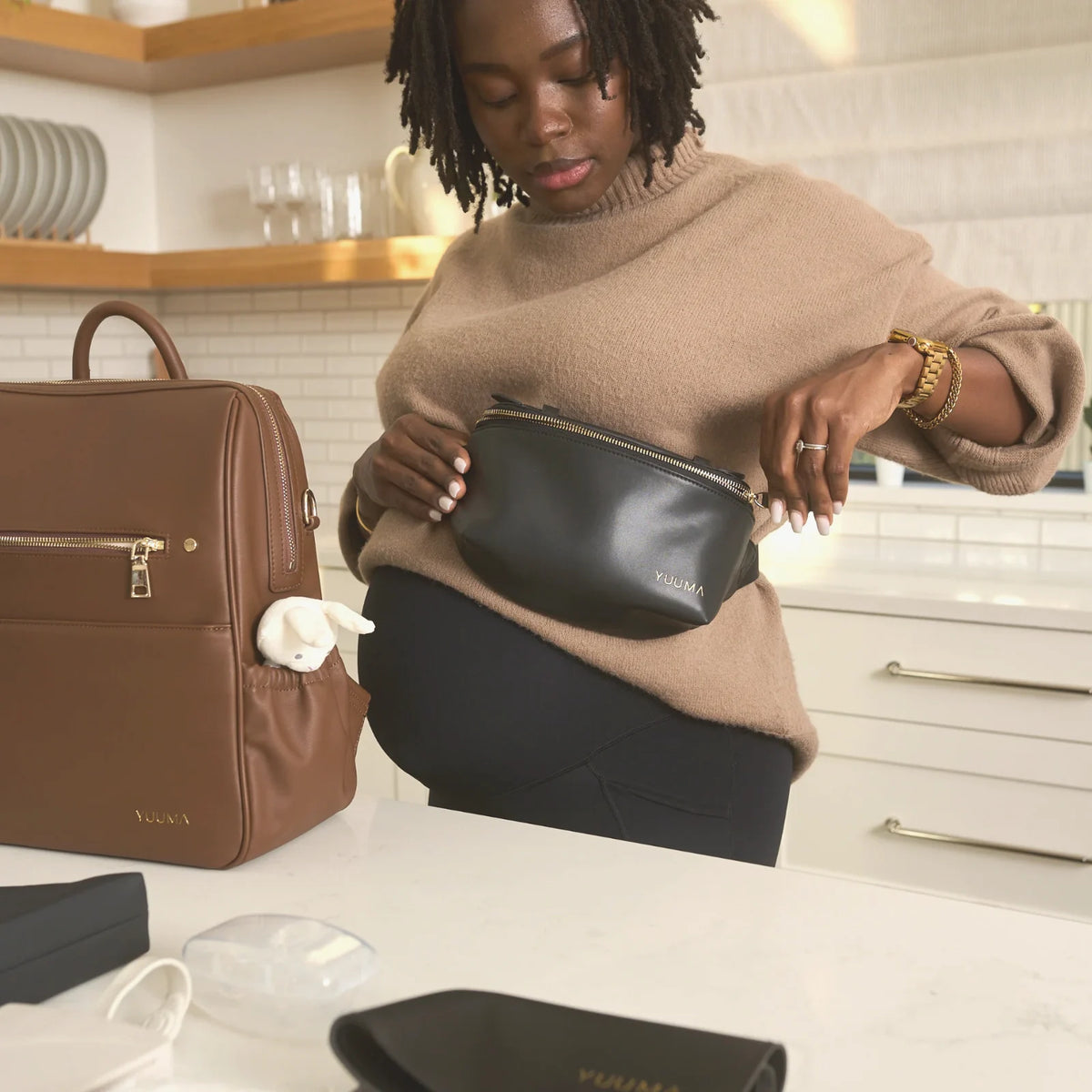 Mom packing the Jolie belt bag next to the Original in a bright kitchen